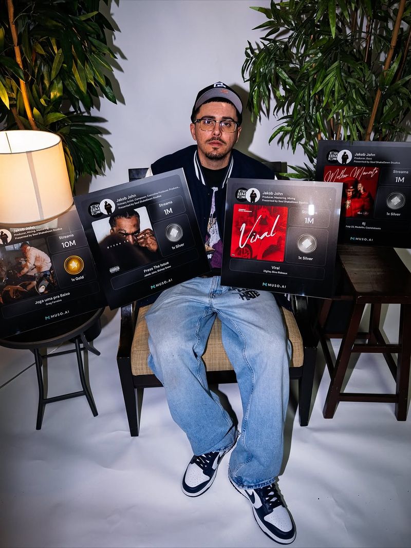 Producer Jakob John surrounded by five Muso.AI track plaques